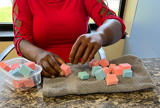 Person engaging in occupational therapy, sorting foam blocks to enhance fine motor skills, at an ARMS healthcare facility.